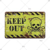 A vintage yellow metal sign with black text that reads KEEP OUT and features a skull and crossbones design.