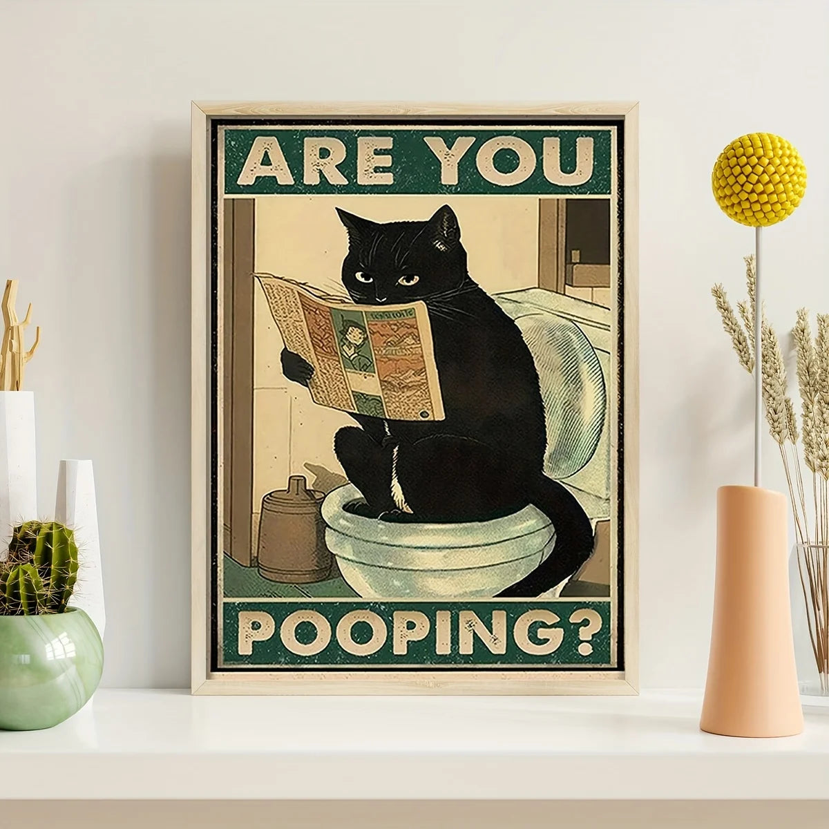 A framed poster featuring a black cat looking surprised while reading, with the text Are you pooping?