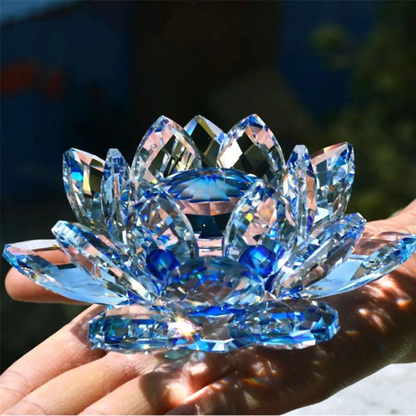 A hand holds a blue crystal lotus flower decorative ornament catching sunlight.