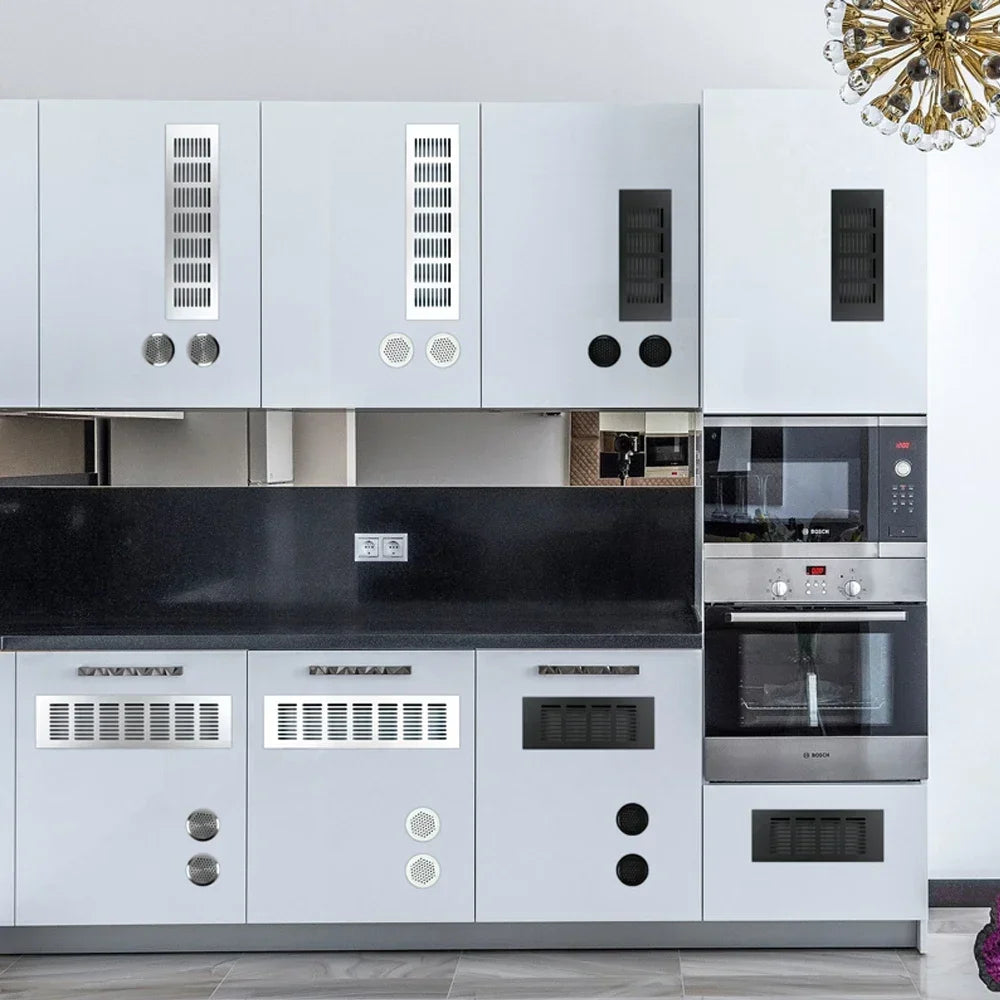 White kitchen cabinets with black countertop and stainless steel appliances featuring rectangular ventilation grilles.