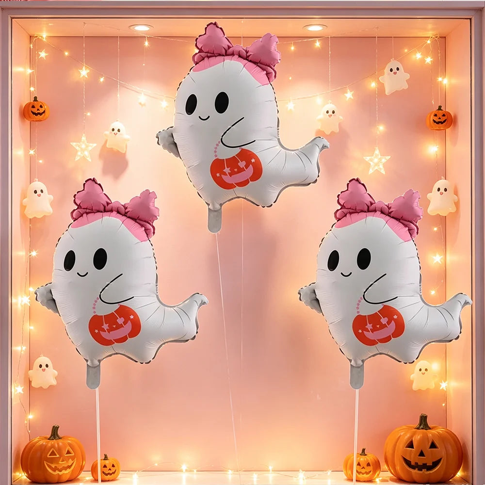 A set of cute white ghost foil balloons with pink bows and orange pumpkin accents decorating a pink background for a Hallowee