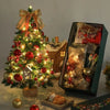 A miniature LED Christmas tree decorated with ornaments and wrapped gifts sits on a wooden base.