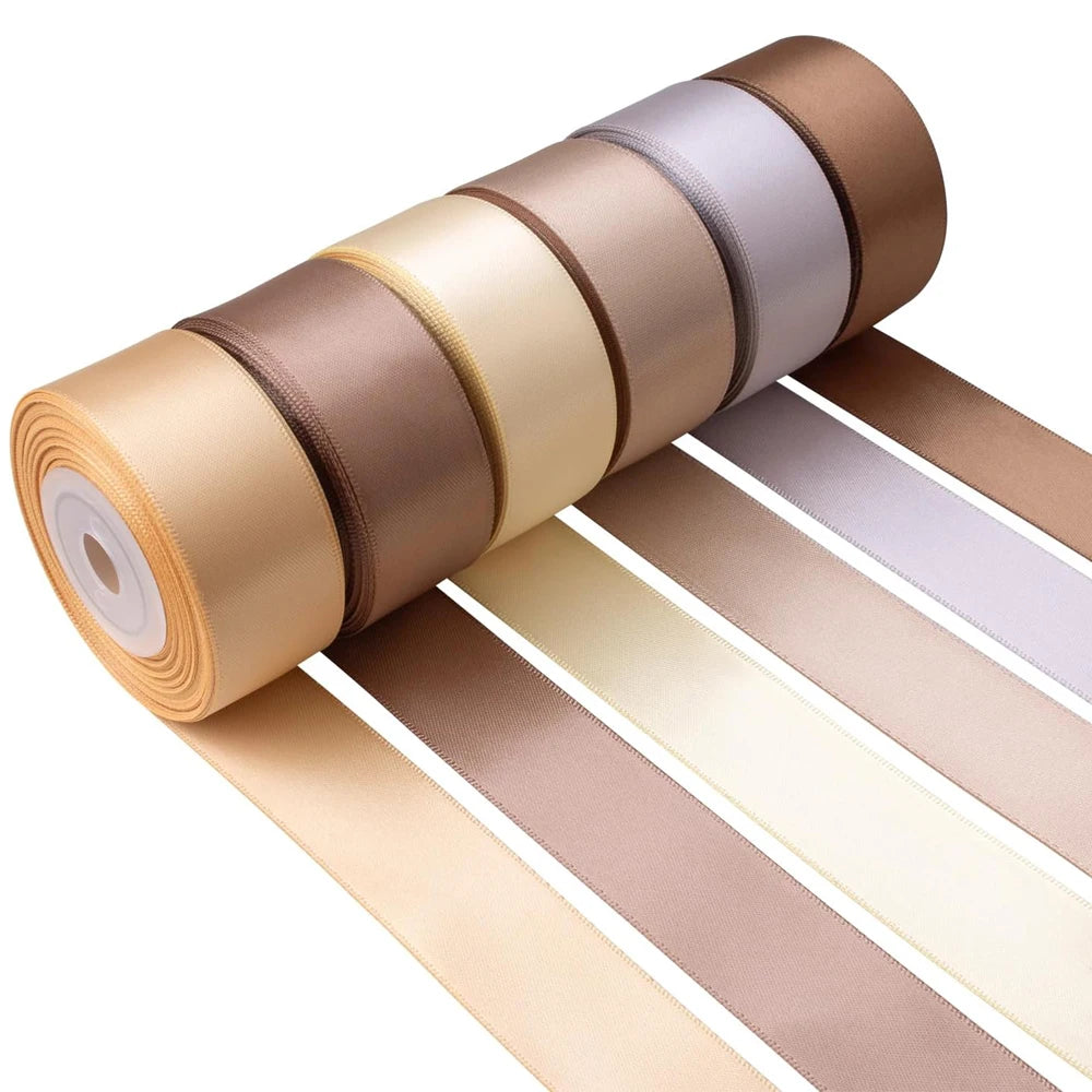 Roll of satin silk ribbon in various shades of beige and brown stacked on a surface