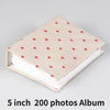 A beige photo album with a light pink patterned cover and white pages.