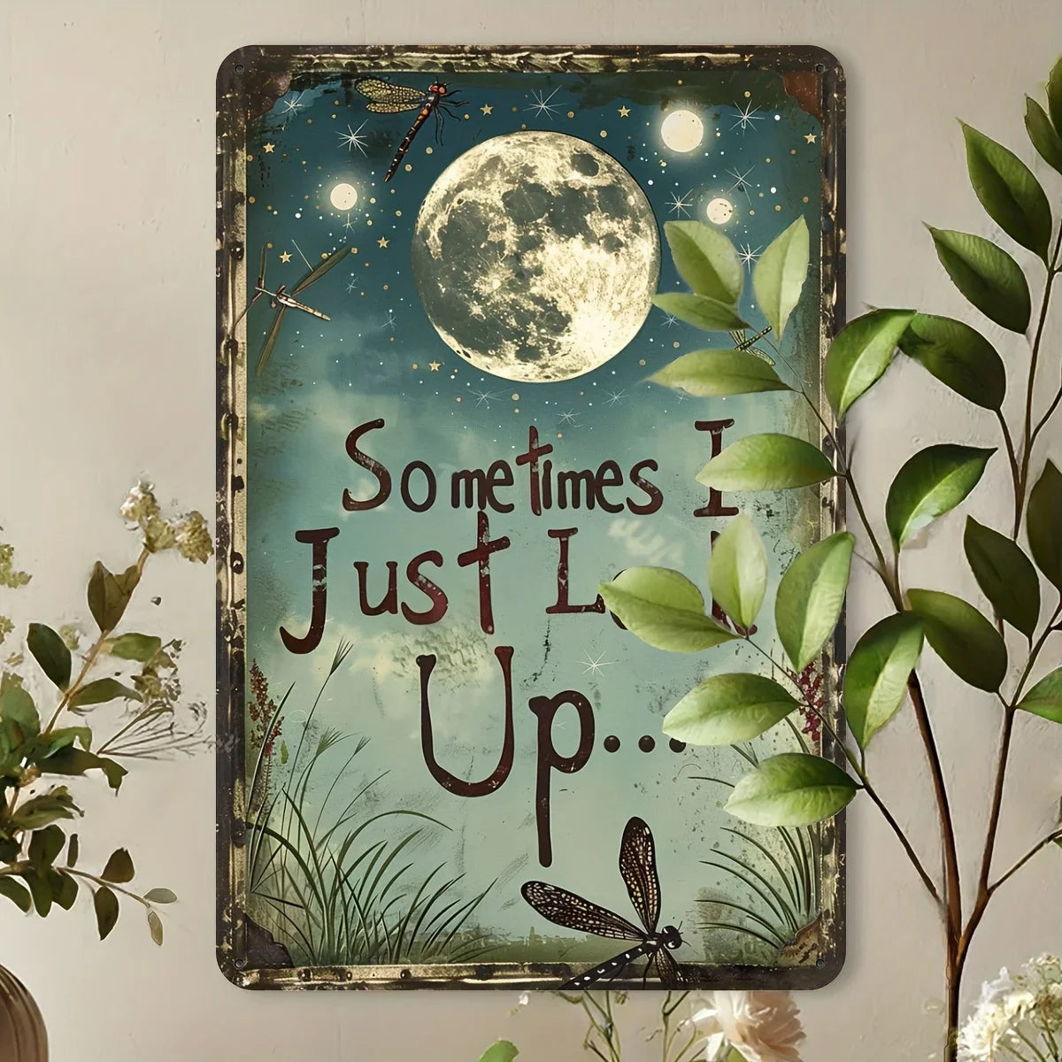 Vintage metal wall decor featuring a quote about the moon and dragonfly on a teal background