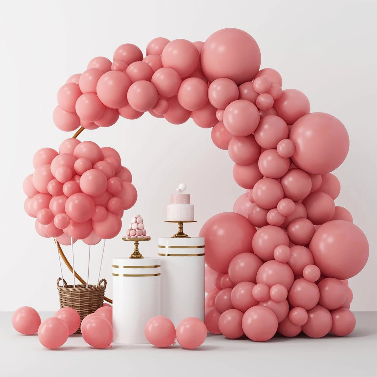 A large, pink balloon arch made of numerous round balloons is displayed on a white surface.