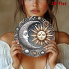 A close-up of a woman holding a silver and gold celestial sun and moon design wall art piece.