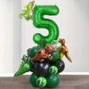 A large green foil balloon shaped like the number 5 is surrounded by various dinosaur-themed balloons.