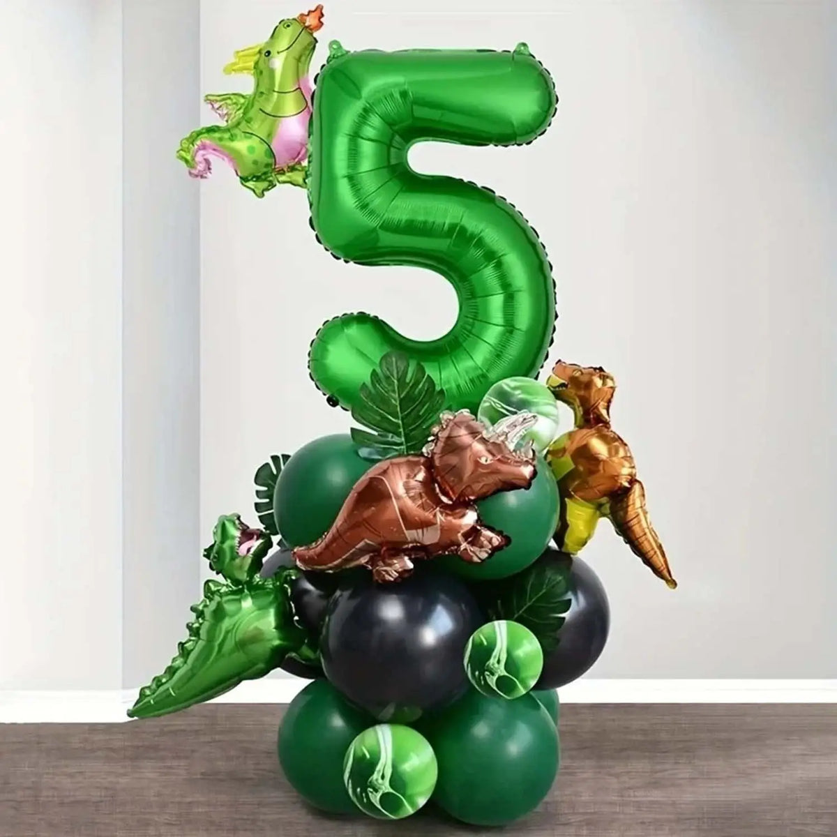 A large green foil balloon shaped like the number 5 is surrounded by various dinosaur-themed balloons.
