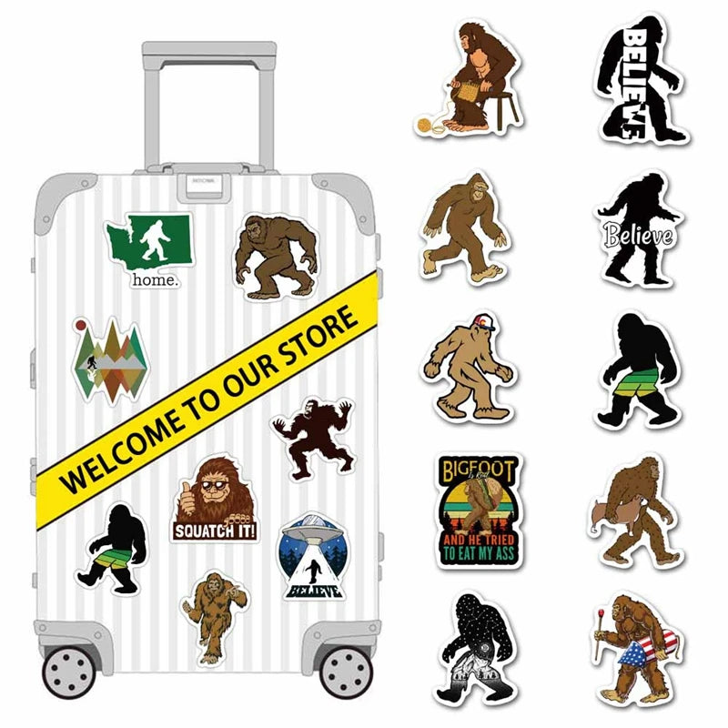 A collection of vinyl stickers featuring Bigfoot and Sasquatch characters on a silver suitcase.