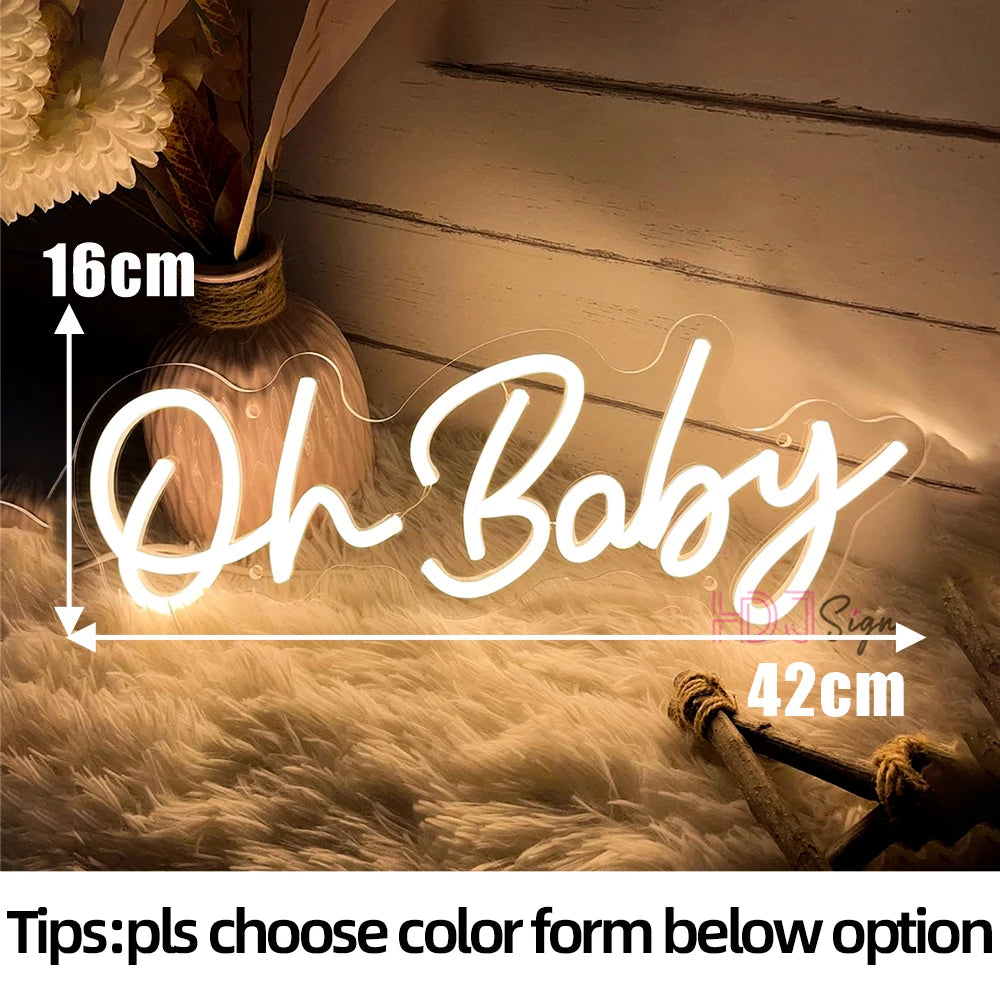 A glowing neon sign spelling out Oh Baby is displayed on a fluffy surface.