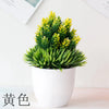 Un pot de bonsaï artificiel avec un feuillage vert vif, exposé sur une surface blanche.