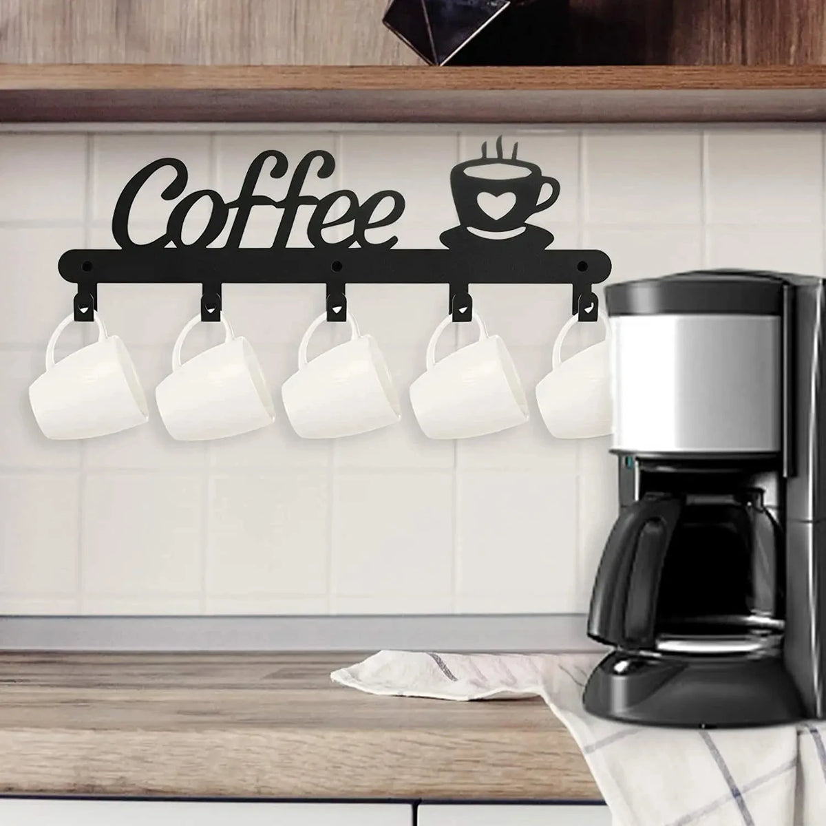 Black wall-mounted coffee mug rack with heart hooks displaying white mugs above a wooden countertop.