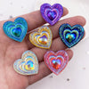 A hand holds a set of twelve heart-shaped iridescent and colorful resin rhinestone flatbacks.