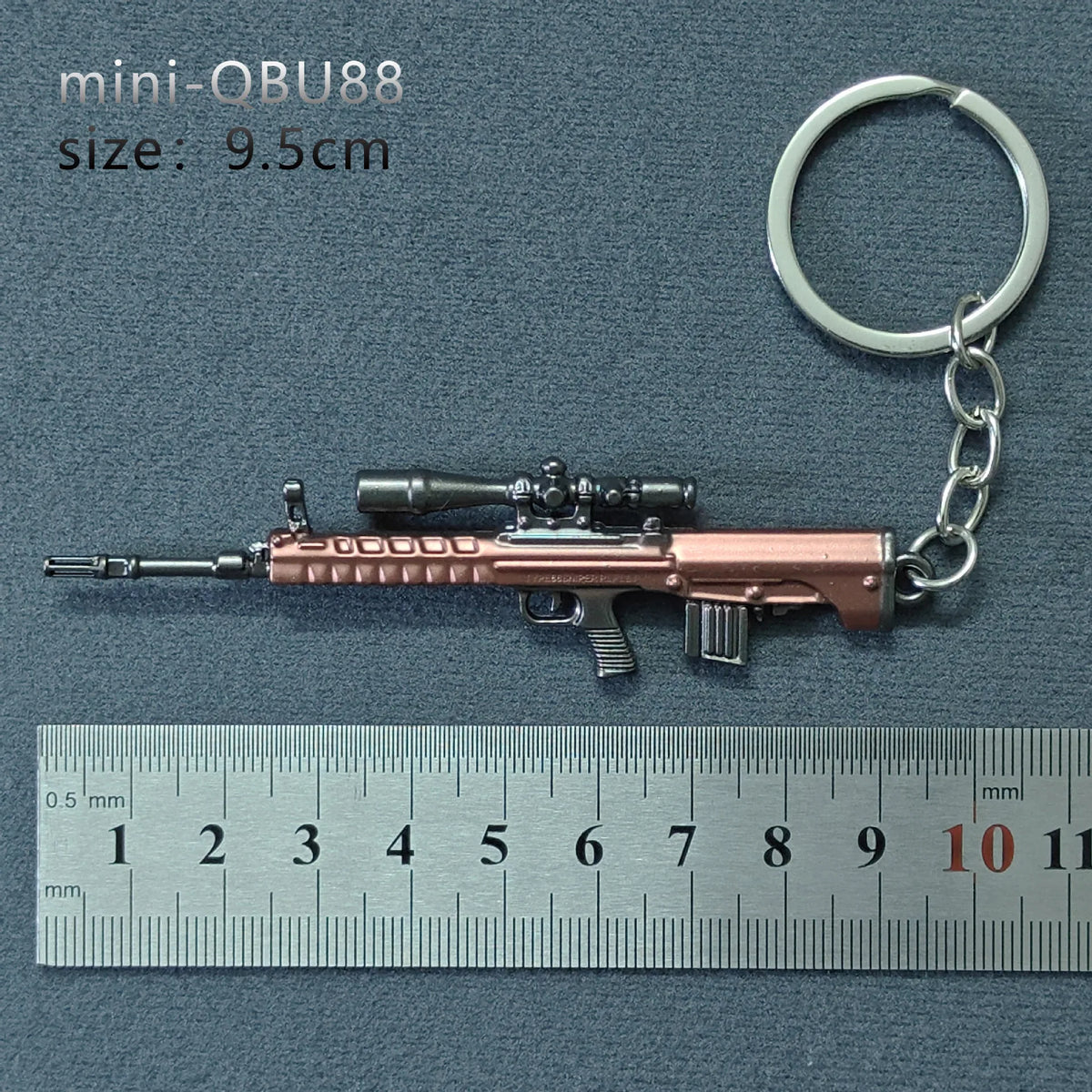 A miniature realistic alloy gun model keychain with a metallic finish, shown next to a ruler.