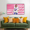 A framed tapestry featuring the American flag design with pink and white stripes and stars, displayed on a wall.