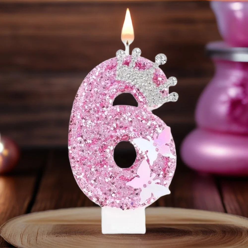 A pink glitter birthday candle shaped like the number six with a butterfly topper