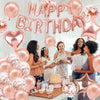 A pink and gold balloon garland featuring hearts, stars, and confetti decorating a birthday setup.