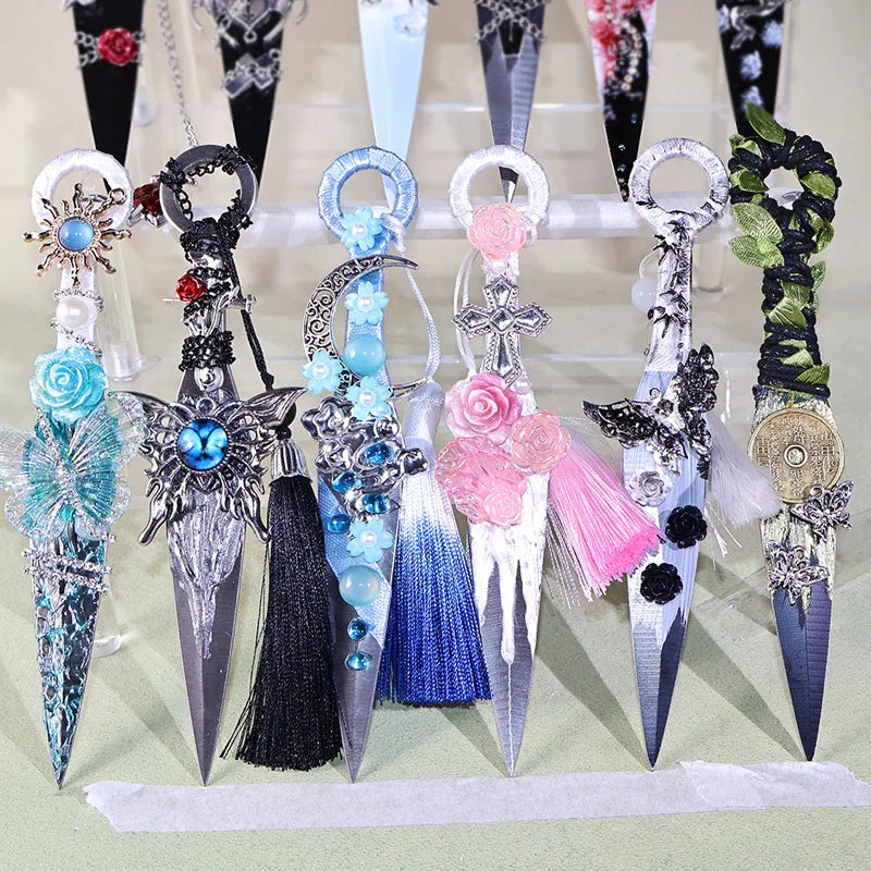 A display of various gothic kunai utility knives with decorative handles and blades in black, silver, and iridescent colors.