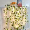 Green artificial leaf string lights draped across a white fabric backdrop for home decor