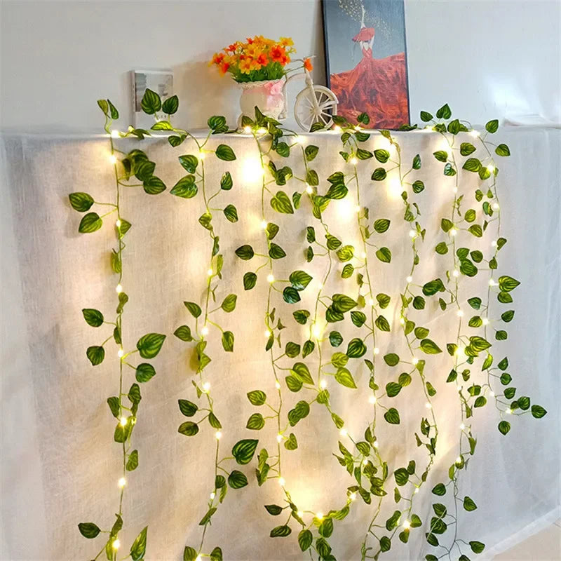 Green artificial leaf string lights draped across a white fabric backdrop for home decor