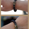 A close-up of a handcrafted Thunder-Wood Pixiu bracelet with semi-jade beads worn on a wrist.