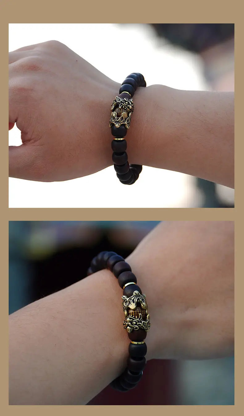 A close-up of a handcrafted Thunder-Wood Pixiu bracelet with semi-jade beads worn on a wrist.