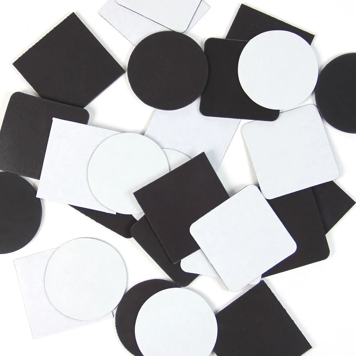A scattered collection of black and white square and circular magnetic photo pieces.