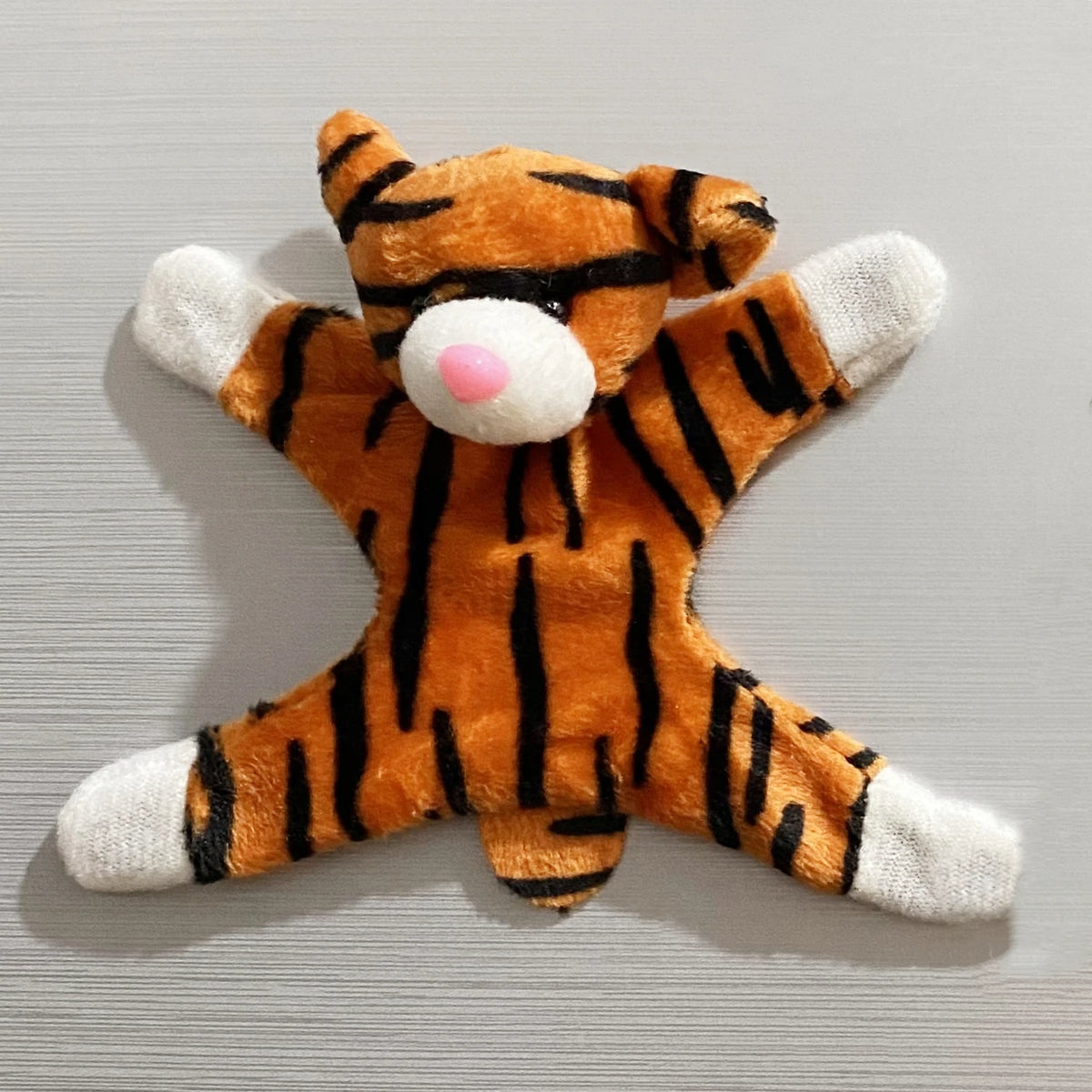 An orange and black striped tiger plush toy with a white snout and paws.