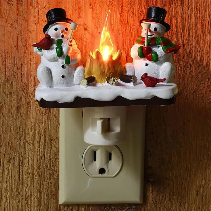 A decoration featuring two white snowmen with black hats and carrots, illuminated by a flickering orange campfire light.