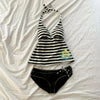 Black and white striped sleeveless top with a tie detail laid flat on a white surface.
