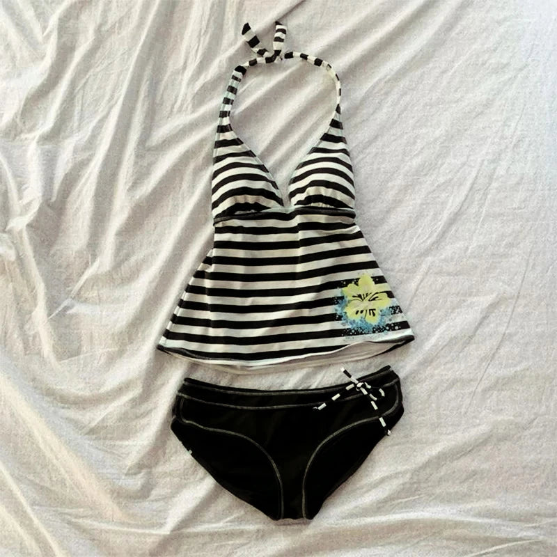Black and white striped sleeveless top with a tie detail laid flat on a white surface.