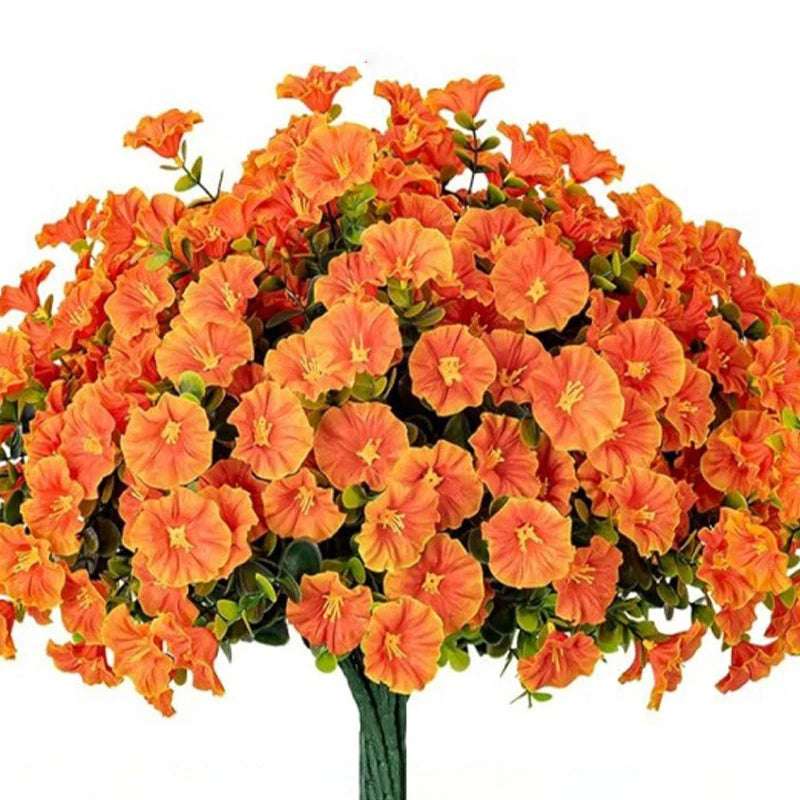 A dense arrangement of bright orange artificial morning glory flowers and green eucalyptus stems.