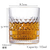 A clear whiskey glass filled with amber liquid, featuring a textured pattern and a glittered rim.