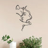 Black metal silhouette wall art depicting a woman and a cat embracing against a beige wall.
