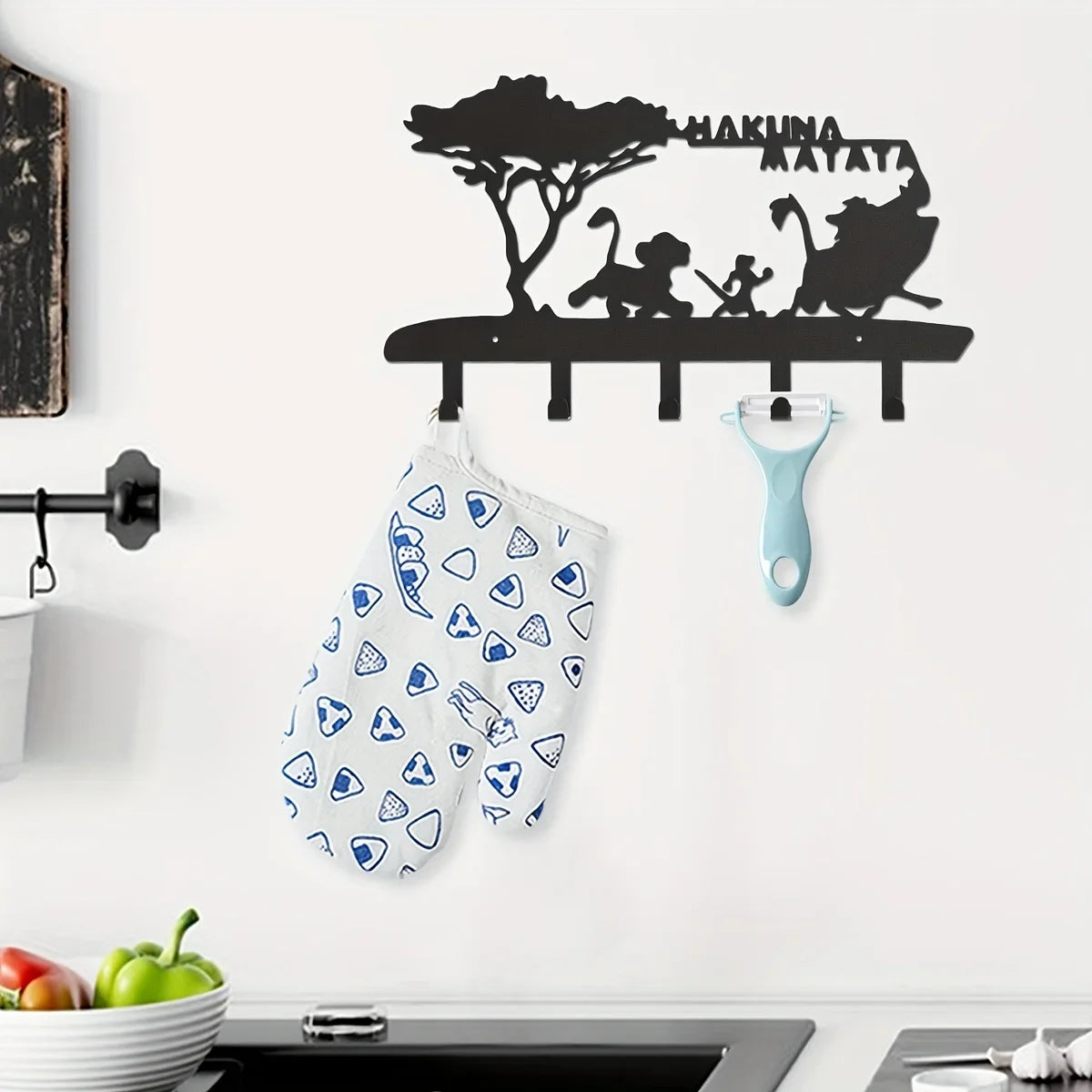 Black silhouette decorative metal key hooks mounted on a white wall above a blue patterned fabric.
