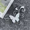 A white vinyl sticker of a butterfly with swirling vines and a small flower on a gray, textured surface.