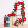 A silk rose vine garland is displayed on a wooden ladder next to books for wedding and home decor.