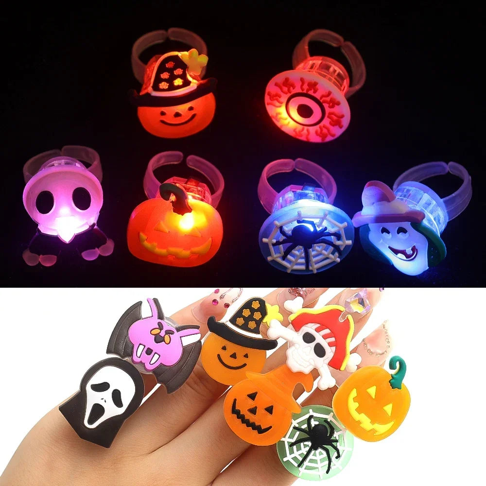 A hand displays several glow-in-the-dark Halloween rings with flashing lights, including pumpkin and skull designs.