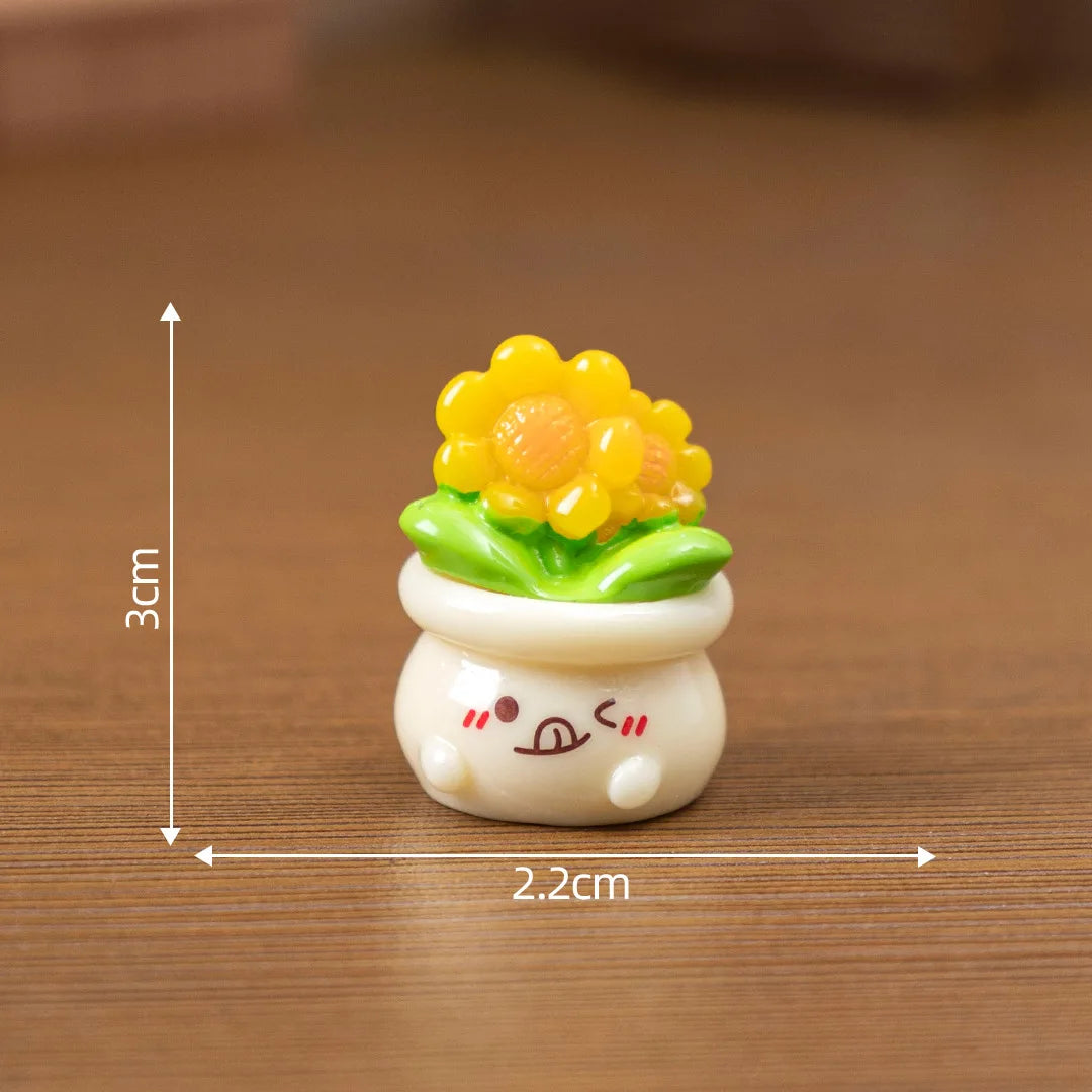 A small resin charm depicting a yellow flower growing from a green leaf and resting on a white base.