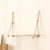 Rustic wooden hanging shelf with rope supports mounted on a white wall.