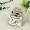 A handmade knitted plush doll resembling a potato with a smiling face resting on a white surface.