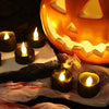 A collection of black LED candles casting a warm white glow next to a carved pumpkin face.