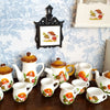 A collection of handcrafted miniature mushroom tableware, including teapots and cups, displayed on a wooden surface.
