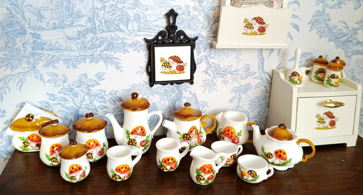 A collection of handcrafted miniature mushroom tableware, including teapots and cups, displayed on a wooden surface.