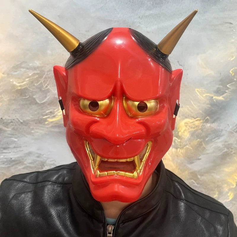 A vibrant red Japanese Hannya demon mask with horns and fierce facial features, worn by a person.