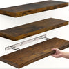 A close-up view of a dark brown wooden floating wall shelf with a silver hidden bracket being installed.