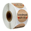 Roll of kraft paper thank you stickers with handwritten text and heart accents