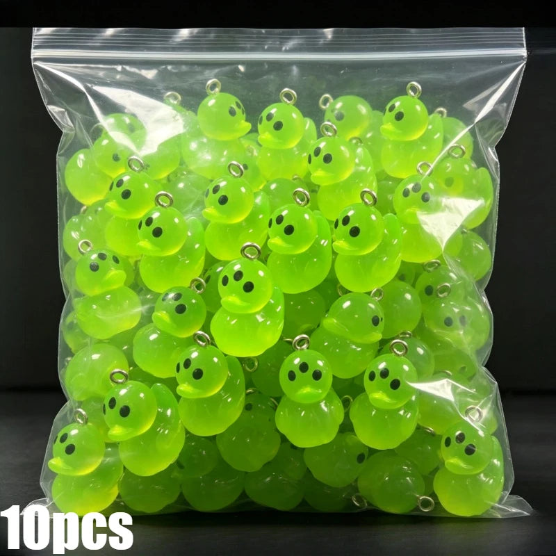 A clear plastic bag filled with numerous bright lime green glow-in-the-dark resin charms shaped like aliens and ducks.