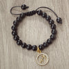 A handmade beaded bracelet with natural black stones and a gold zodiac charm